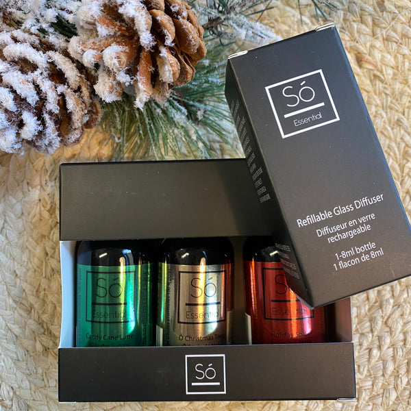 Scented diffuser bottles with packaging on a textured surface with decorative elements.