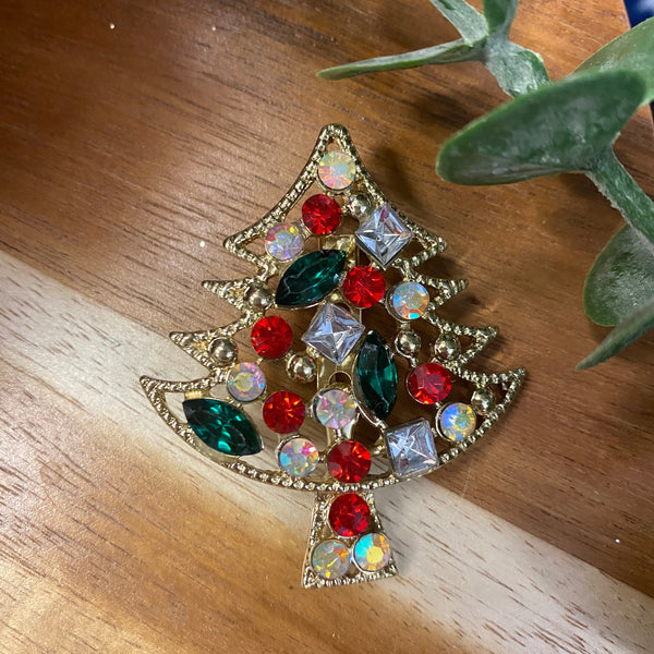 Decorative brooch with colorful gemstones on a wooden surface