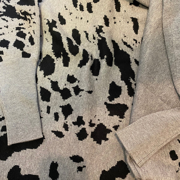 Gray sweater with black and white pattern on a plain background