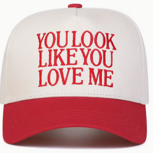 Cap with 'YOU LOOK LIKE YOU LOVE ME' text in red on a white background