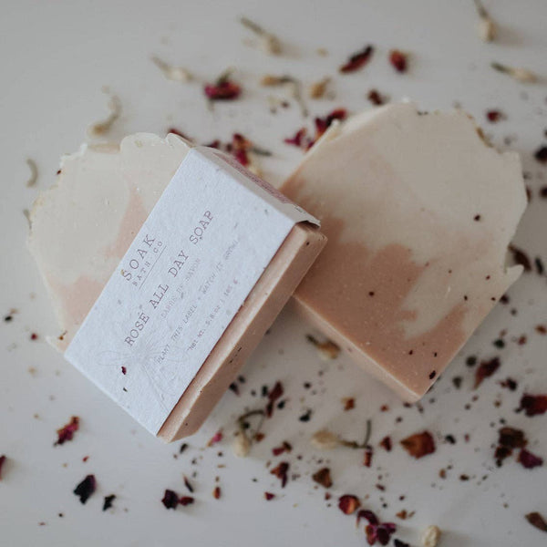 Two bars of soap with a label on a surface with dried herbs