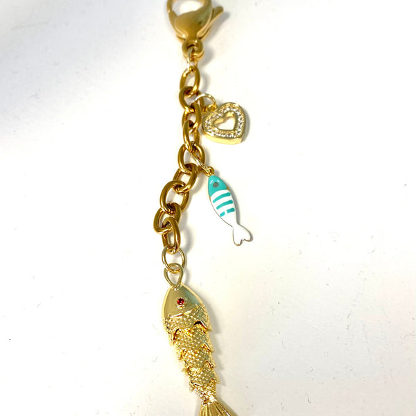 A gold-tone fish charm keychain or bag clip with a lobster clasp, featuring a larger textured gold fish, a smaller striped blue and white fish, and a small heart-shaped charm on a white background.