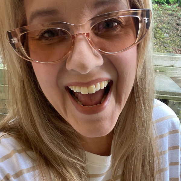 Person wearing large sunglasses and a plaid shirt with a blurred background