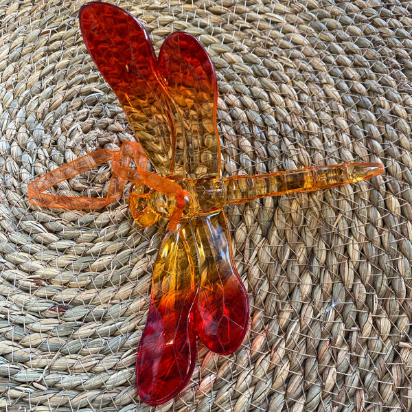 Decorative amber dragonfly on a woven surface