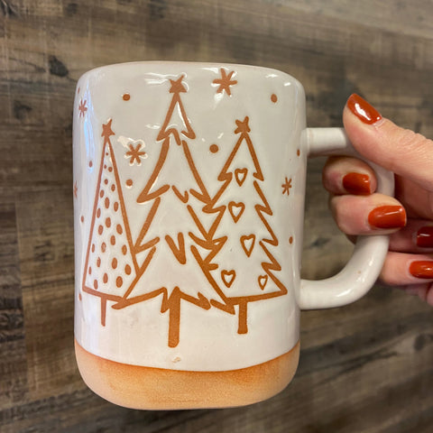 Mug with tree design held by a hand on a wooden surface
