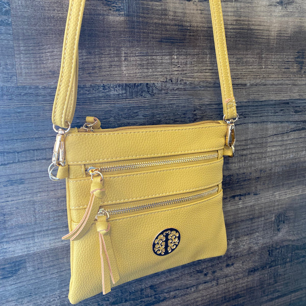 Yellow crossbody bag with a visible brand logo on a blue denim background