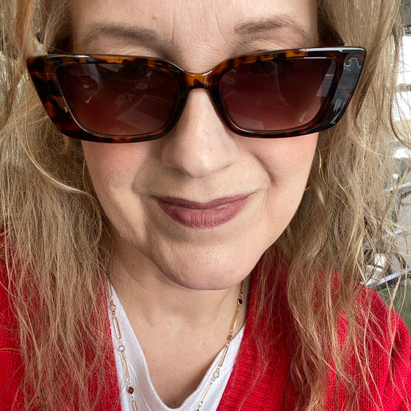 Close-up of a person wearing sunglasses with a red garment in the background