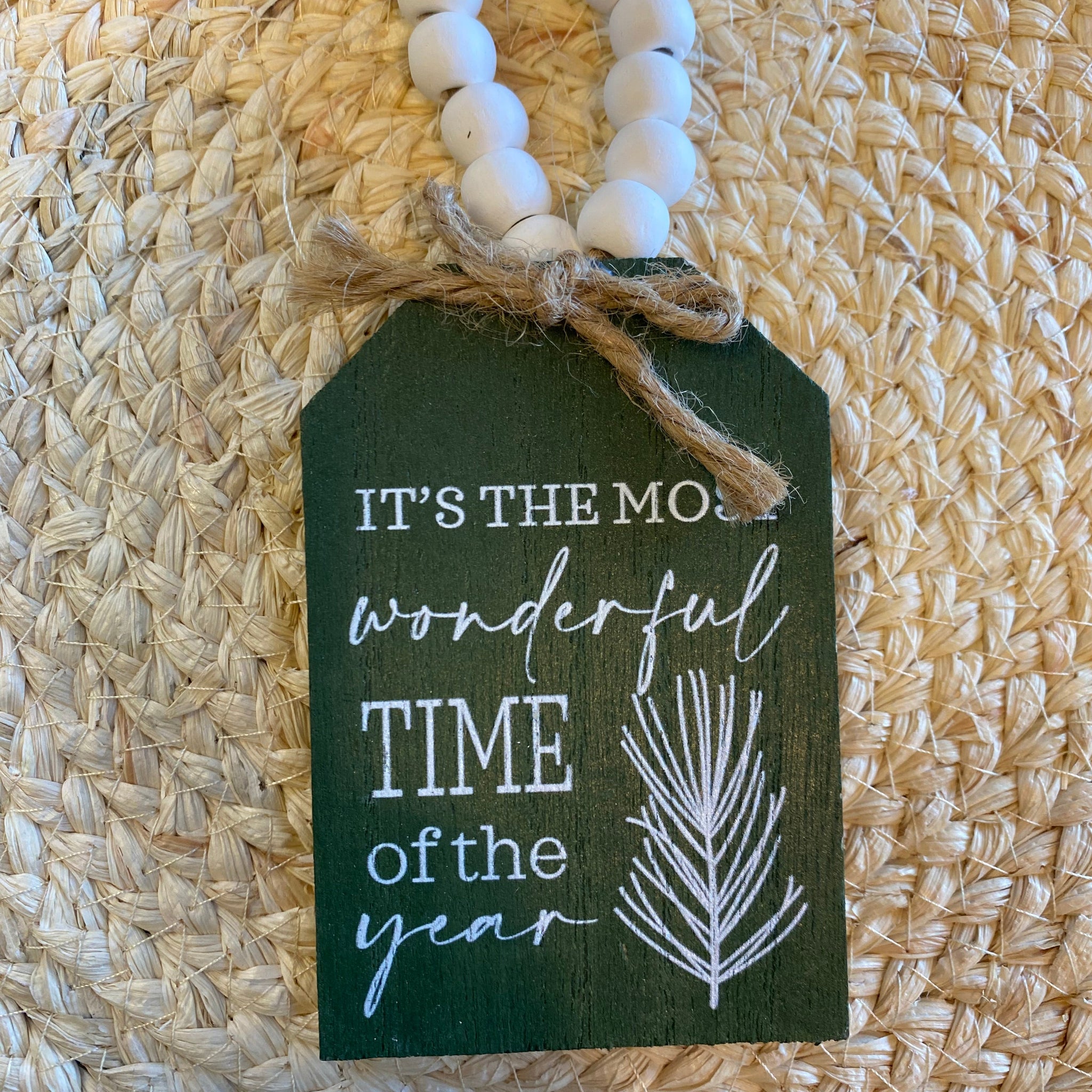 Decorative tag with 'It's the most wonderful time of the year' text on a woven mat.