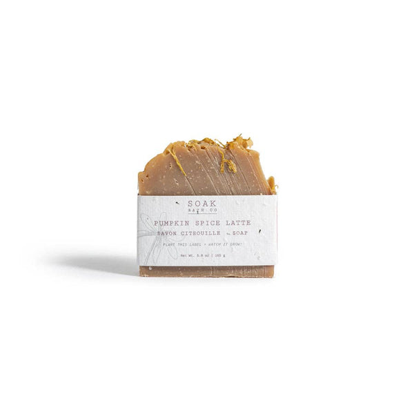 A single bar of handmade soap labeled 'Pumpkin Spice Latte' by 'SOAK by co.', featuring a textured golden-brown top and a white paper label, set against a plain white background.