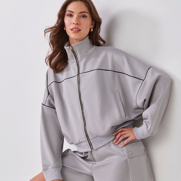 Woman wearing a gray tracksuit against a white background