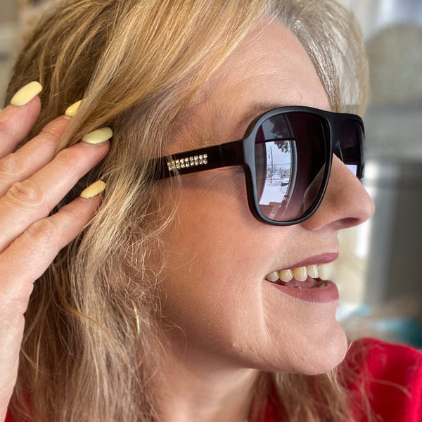 Woman wearing sunglasses and adjusting her hair with a blurred background