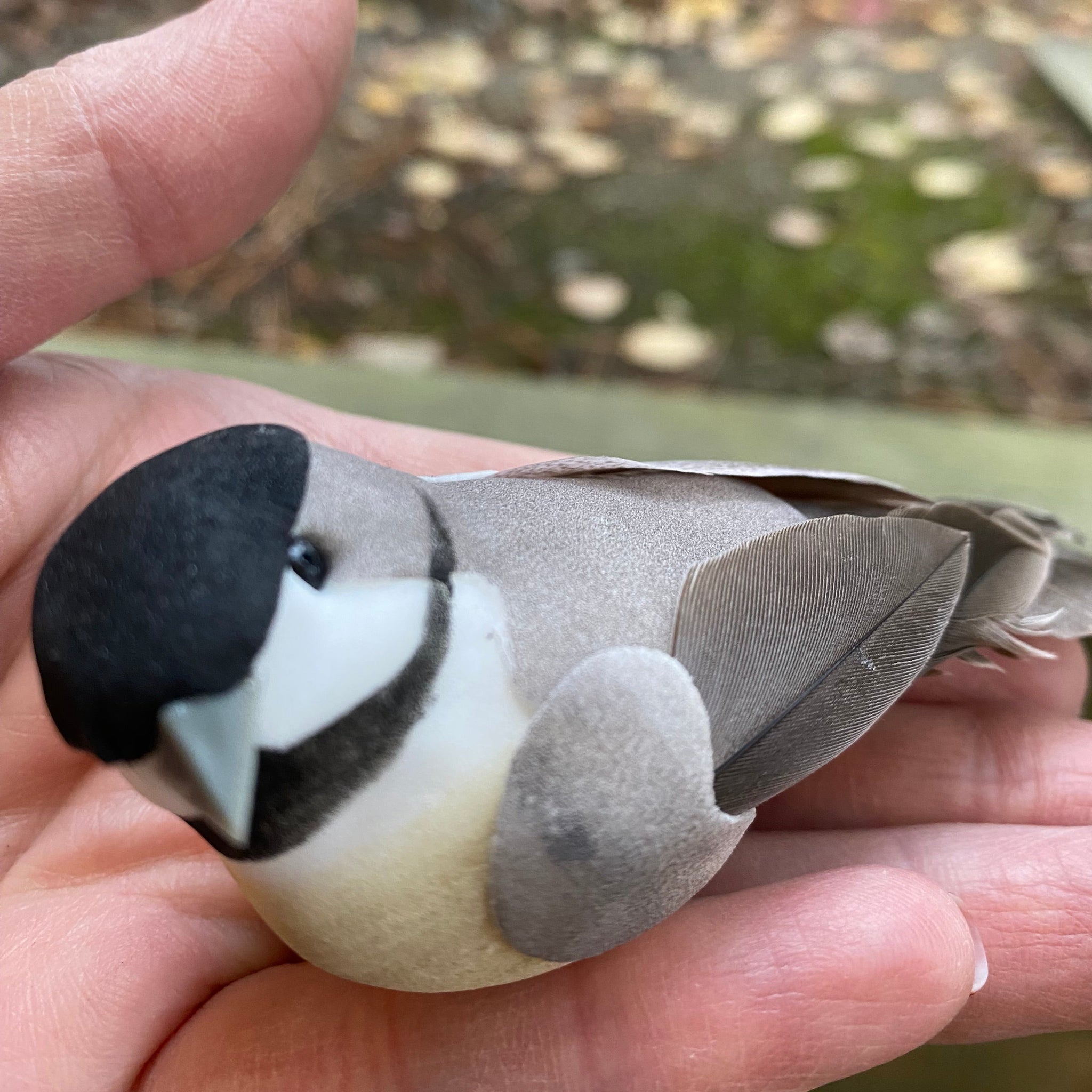 Hand holding a small bird-shaped object with a blurred background