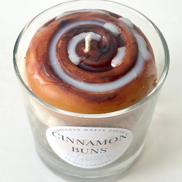 Candle in the shape of a cinnamon bun with a label on a white background