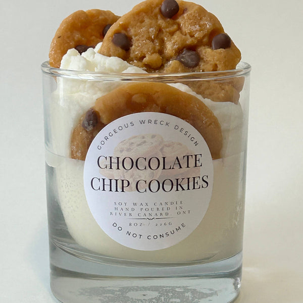 Candle in a glass jar with chocolate chip cookies on top and a label on a white background