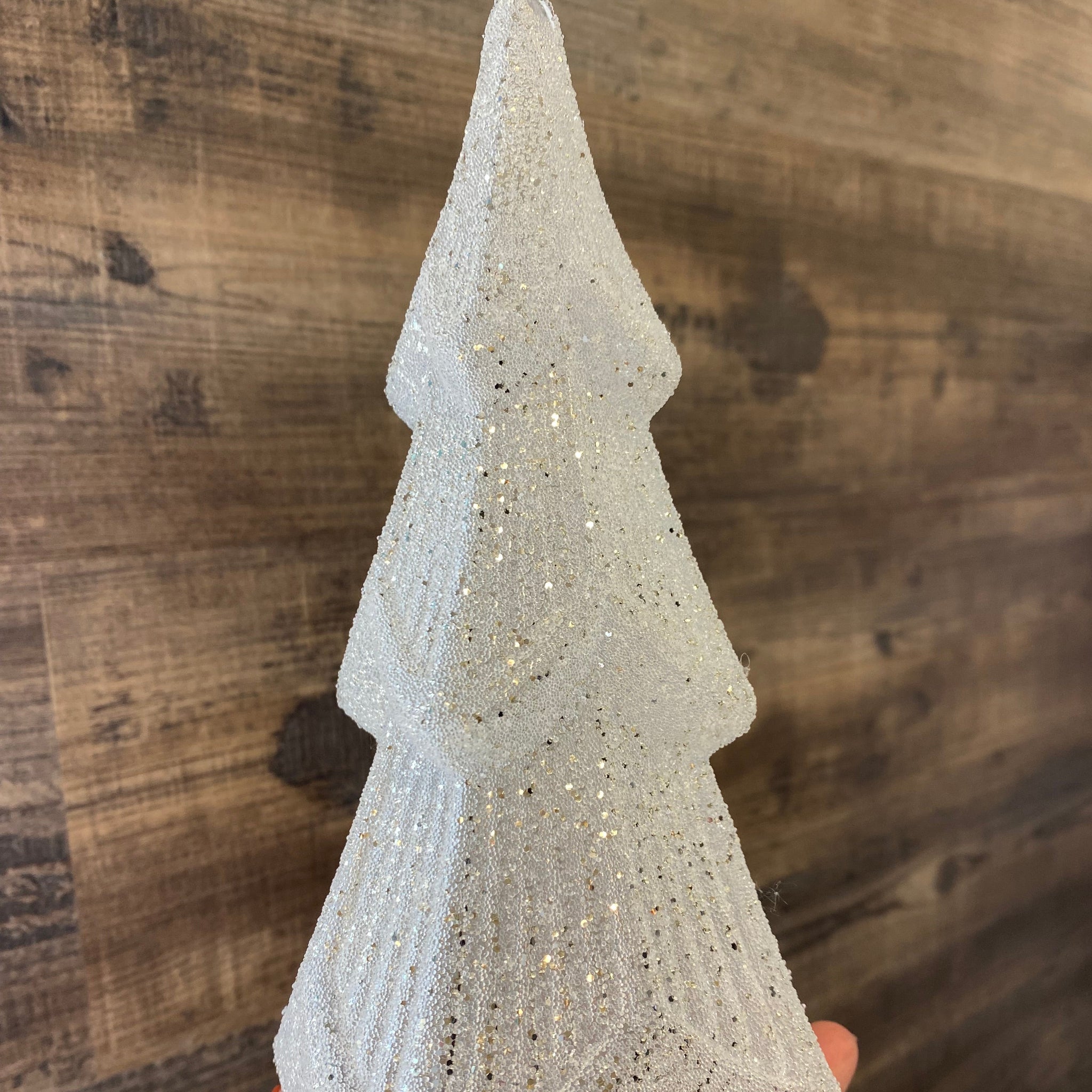 Hand holding a textured stone-like object on a wooden surface