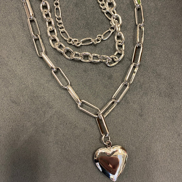Silver chain necklace with a heart-shaped pendant on a gray surface