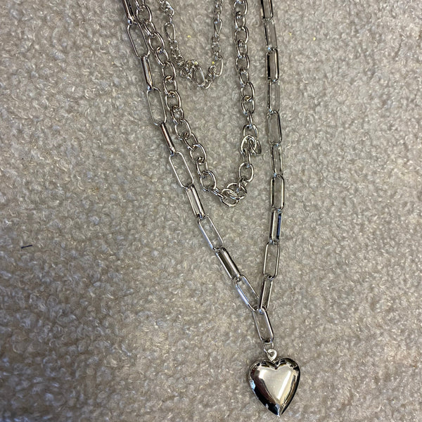 Silver chain necklace with a heart-shaped pendant on a gray surface