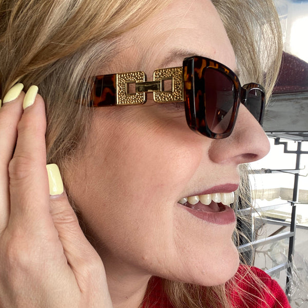 Person wearing sunglasses with a gold frame and tortoiseshell pattern, lying down.