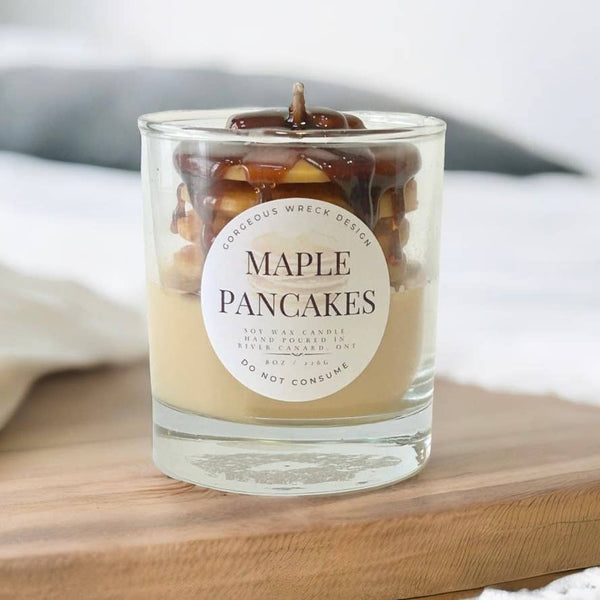 Candle with 'Maple Pancakes' label on a wooden surface