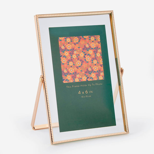 Gold photo frame with a floral patterned photo on a white background