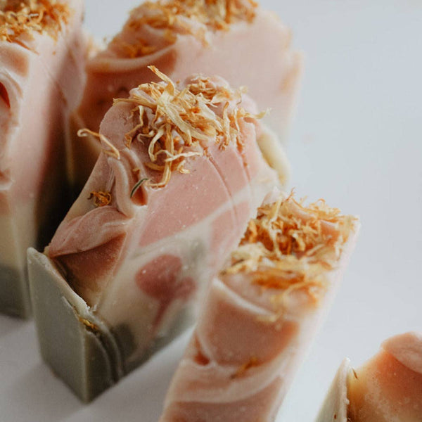 Close-up of pink soap bars with gold flakes on a white background