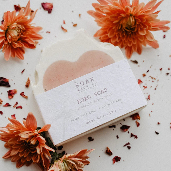 Heart-shaped soap with a label surrounded by orange flowers on a light background
