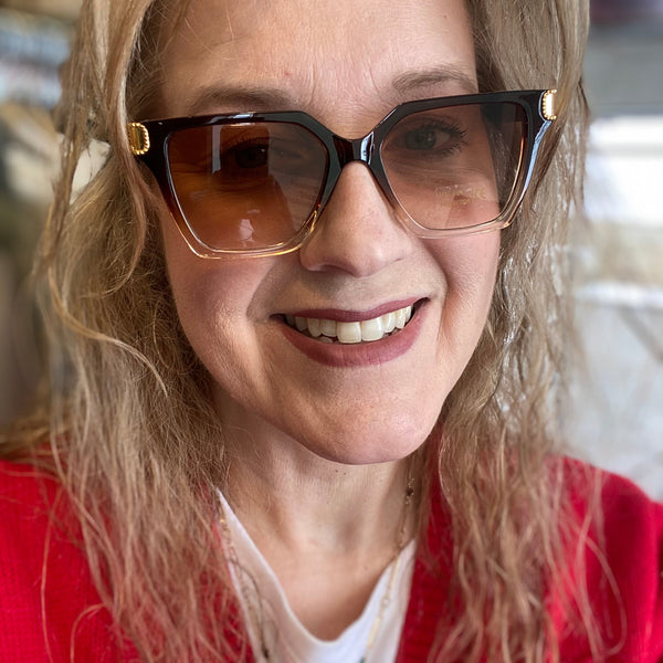 Woman wearing sunglasses and a red sweater indoors