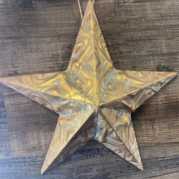 A metallic gold five-pointed star ornament hanging against a dark wood plank background.