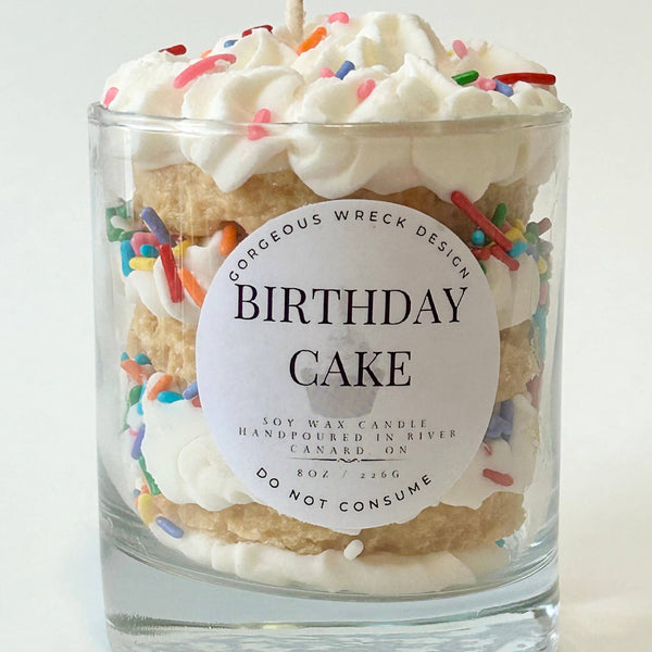 Birthday cake-themed candle with decorative elements on a white background