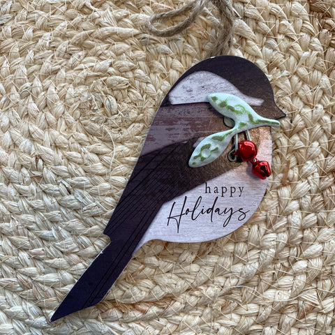 Decorative wooden ornament shaped like a bird with 'Happy Holidays' text on a woven surface