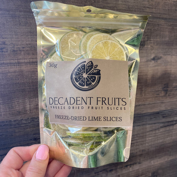 Packaged freeze-dried lime slices held by a hand on a wooden surface