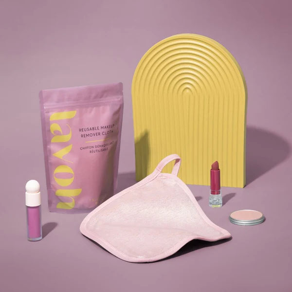 Makeup removal products including reusable makeup remover cloths, a pink pouch, and lip products on a purple background.