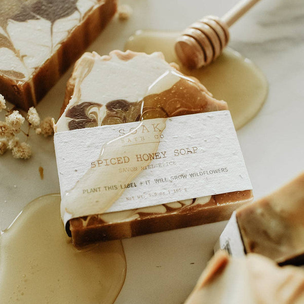 Spiced honey soap with a label on a marble surface with honey and a honey dipper.