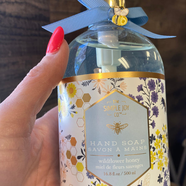 Bottle of hand soap with floral label held by a hand