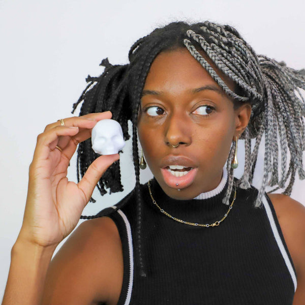 Person holding a white spherical object against a plain background
