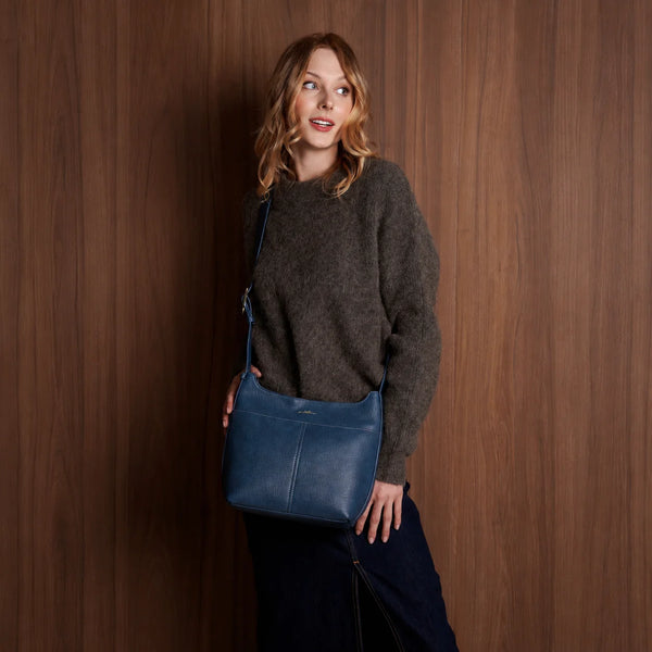 Woman holding a blue leather bag against a wooden background