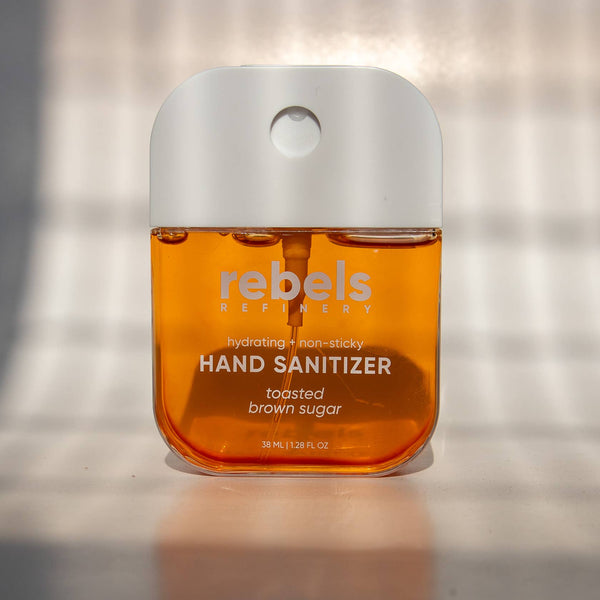 Hand sanitizer bottle with 'rebel's' branding on a reflective surface