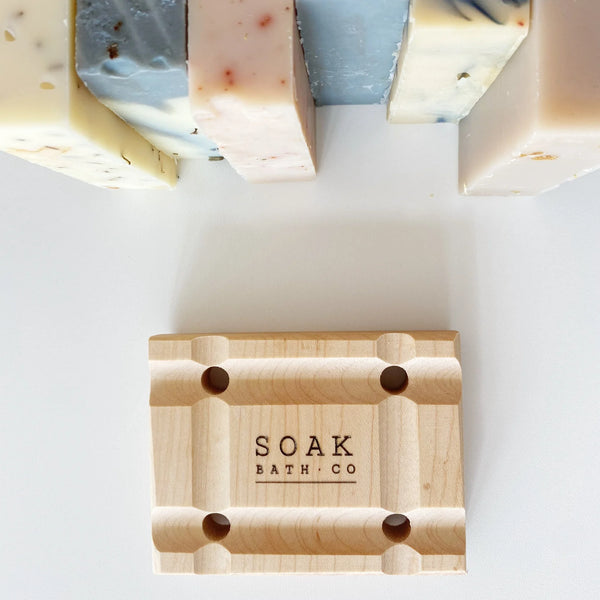 Wooden soap dish with 'SOAK BATH CO' branding on a white background
