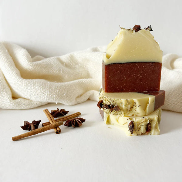 Stack of layered soap bars with star anise and cinnamon on a white background
