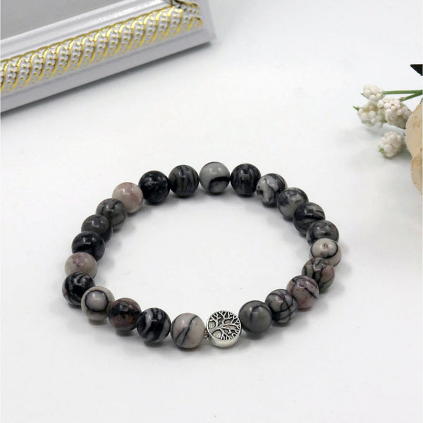 Beaded bracelet with a tree of life charm on a white surface
