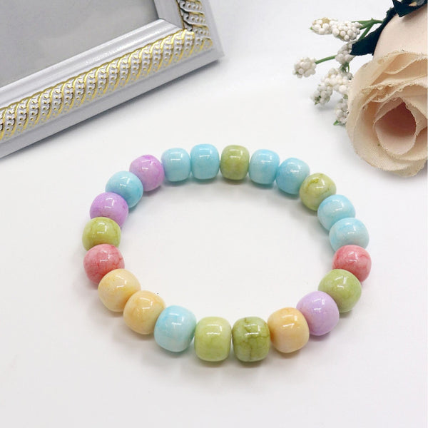 Multicolored beaded bracelet on a white surface with a decorative frame and flowers in the background.