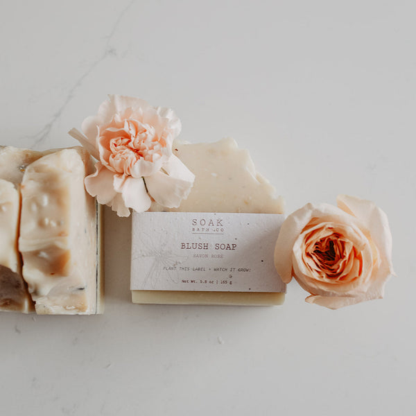 Bar of soap with a floral label and two roses on a light background