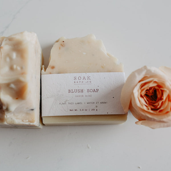Two bars of soap with a label and a rose on a white background
