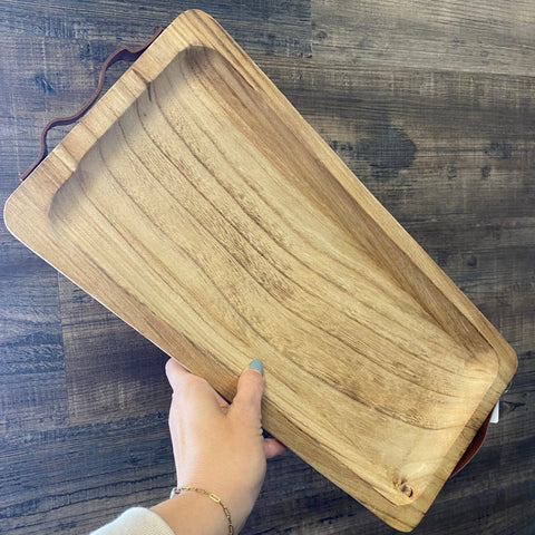 Wooden tray held by a hand on a wooden surface