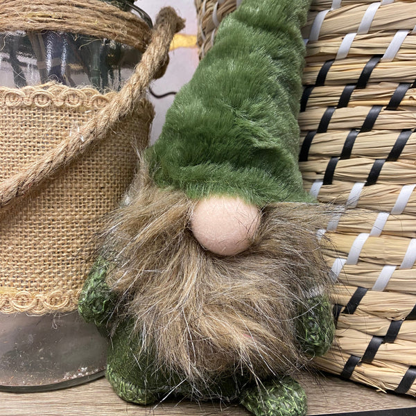 Decorative gnome with green hat and brown beard on a woven surface