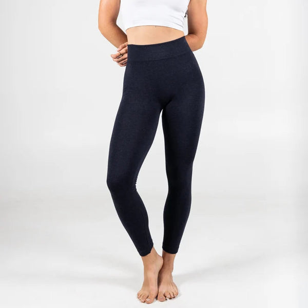 Woman wearing black leggings and a white crop top on a white background
