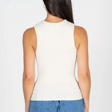 A woman viewed from the back wearing a ribbed sleeveless knit top in off-white and blue jeans, set against a plain light gray studio background.