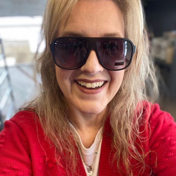 Person wearing sunglasses and a red sweater with a blurred background