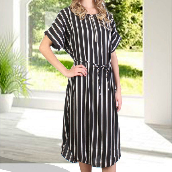 Woman wearing a black and white striped dress in a bright room with large windows.