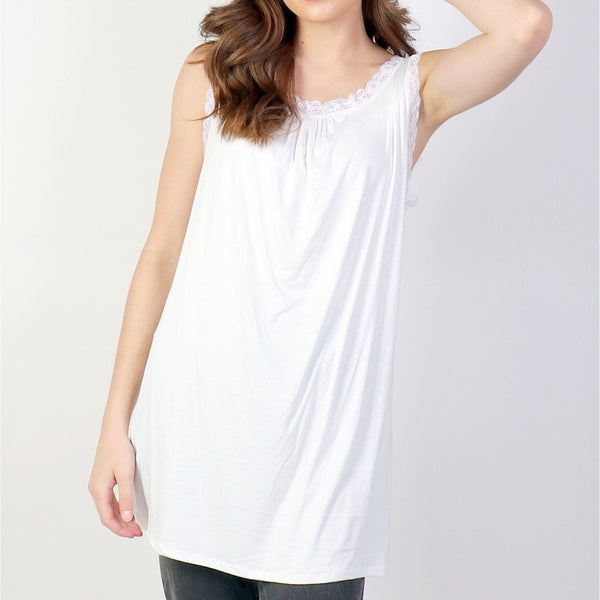 Woman wearing a white sleeveless top against a plain background